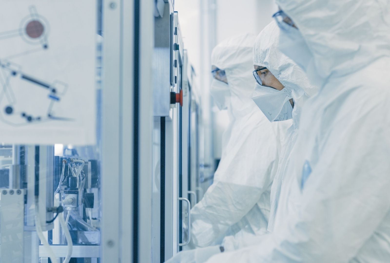 Cleanroom workers in protective suits at semiconductor fab equipment
